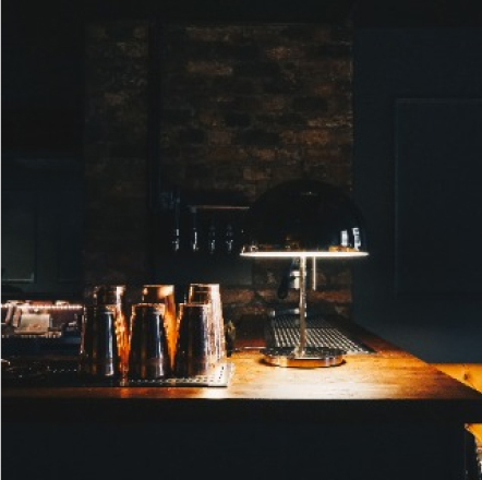 Dimly lit bar top with shaker glasses sitting off to the side.
