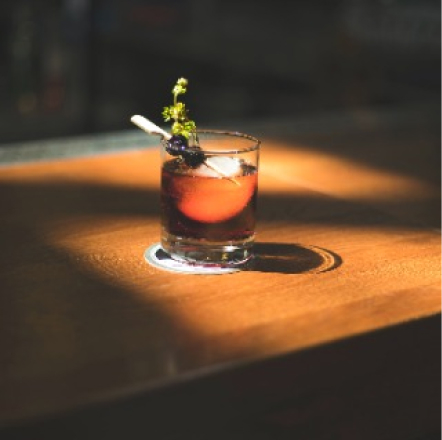 Old fashioned sitting on a bartop, lit by natural light through a window.